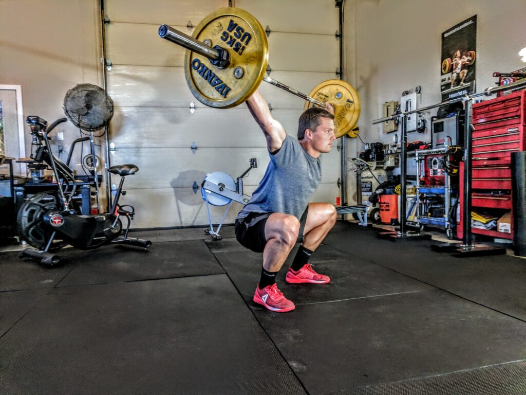 Man performing a CrossFit clean & jerk with barbell overhead